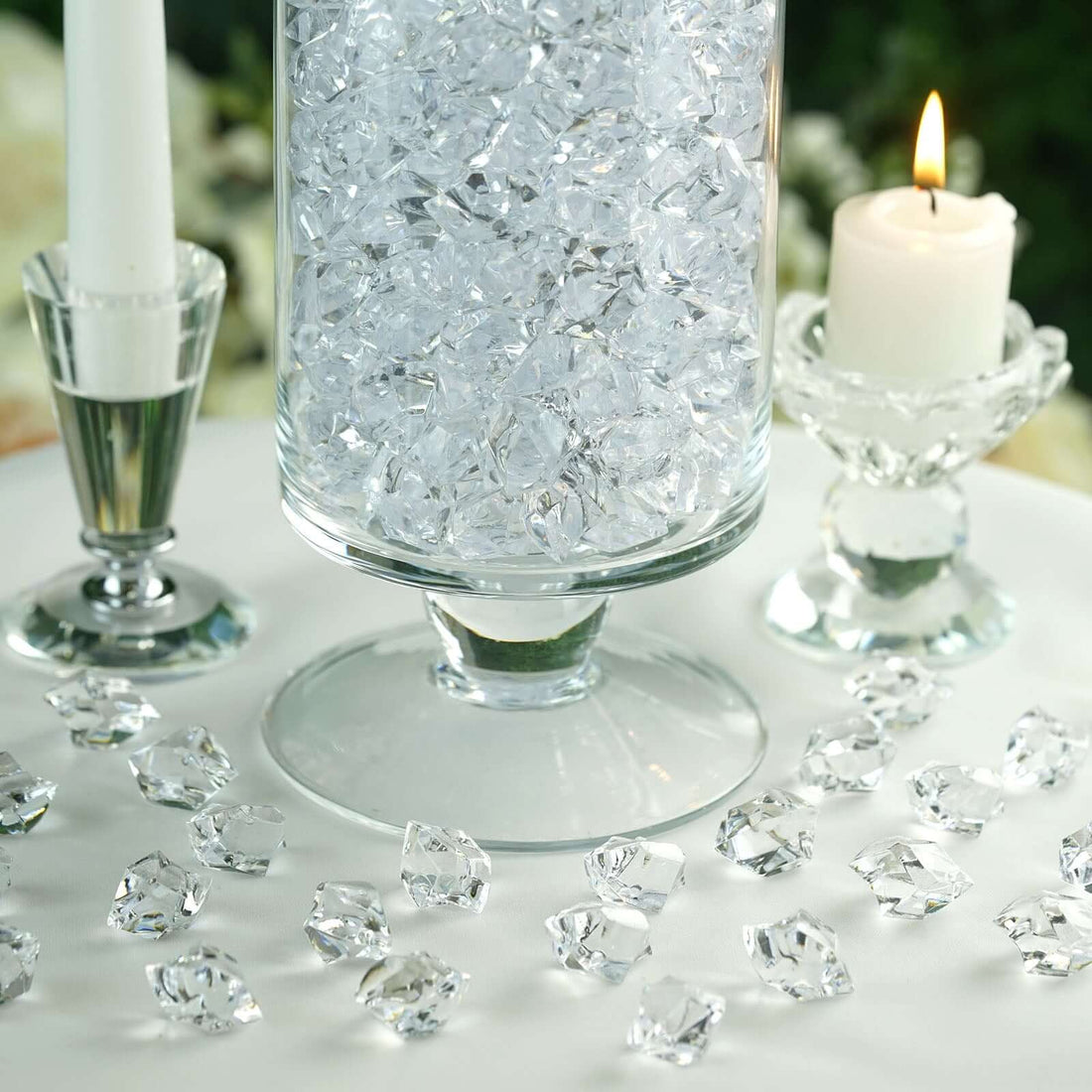 Crystal decorative gems arranged around a glass vase with candles.