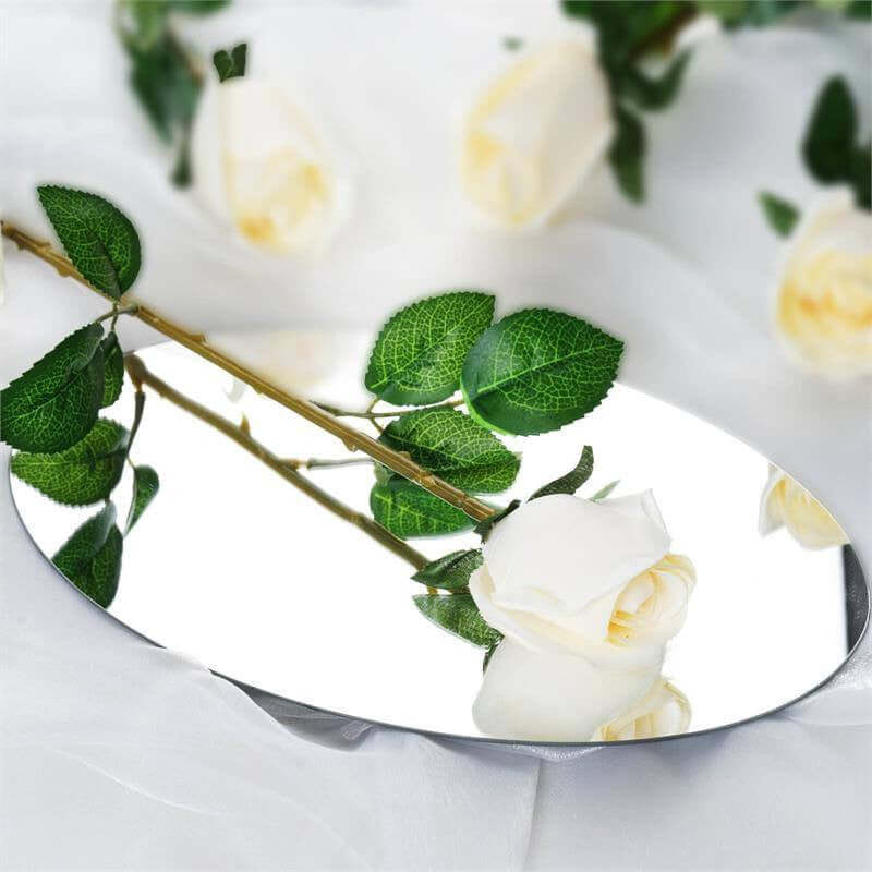 Oval mirror with a white rose and green leaves reflection.