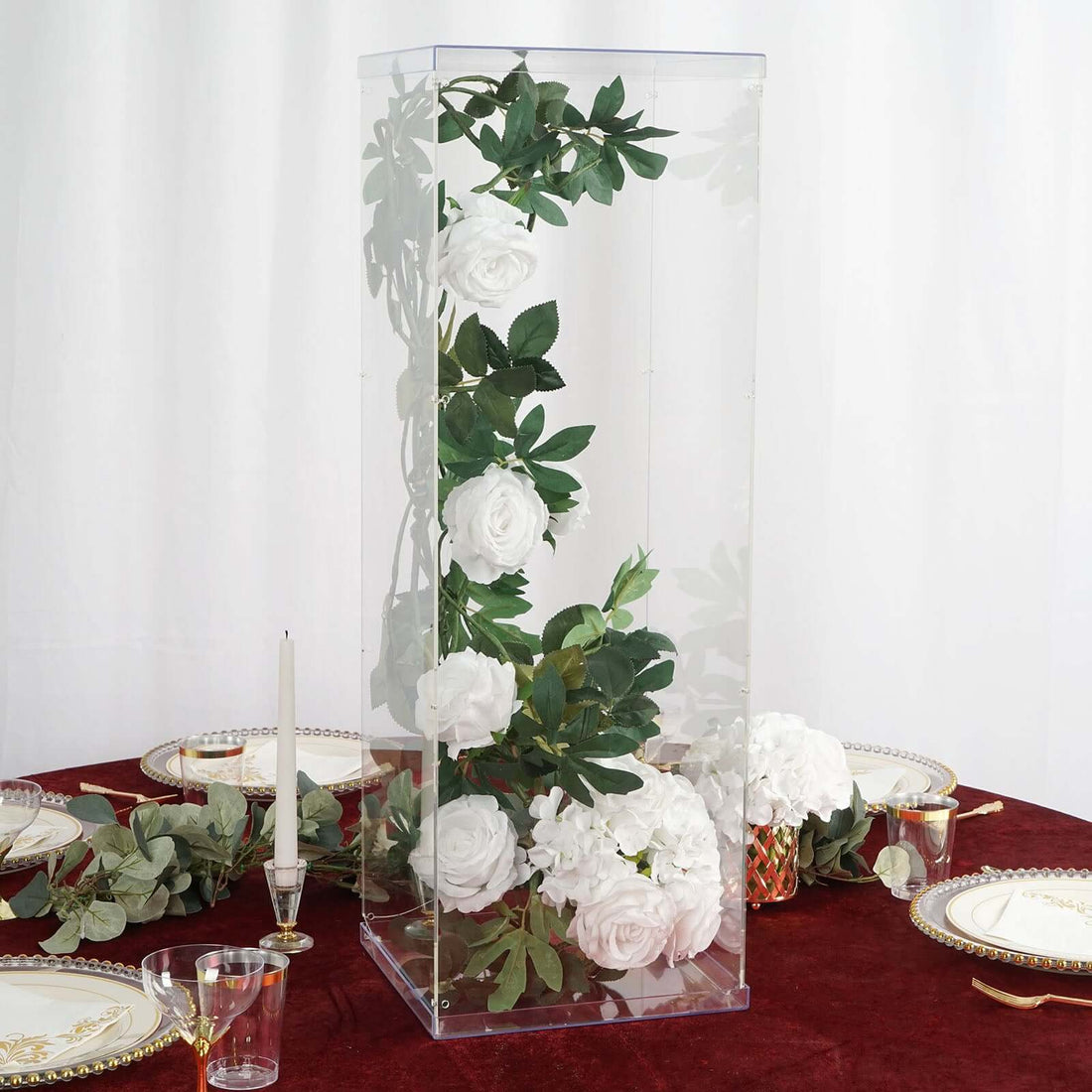 Clear floral centerpiece display with white roses and greenery.