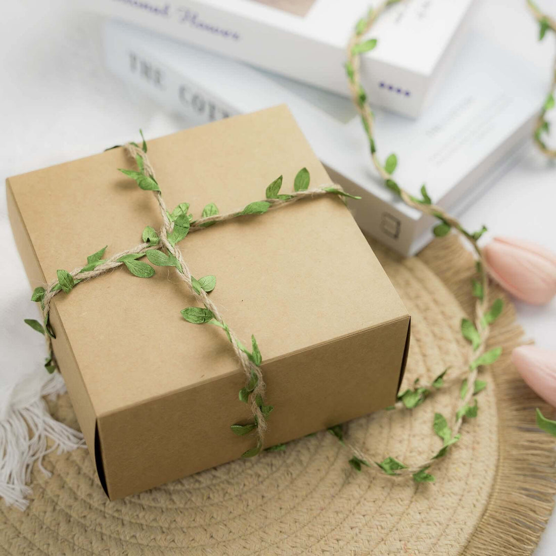 Gift box adorned with twine and greenery on a natural placemat.
