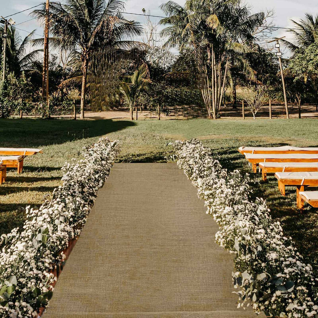 Outdoor wedding aisle with floral arrangements and wooden benches.