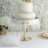 Elegant white wedding cake on a decorative stand with feather trim.