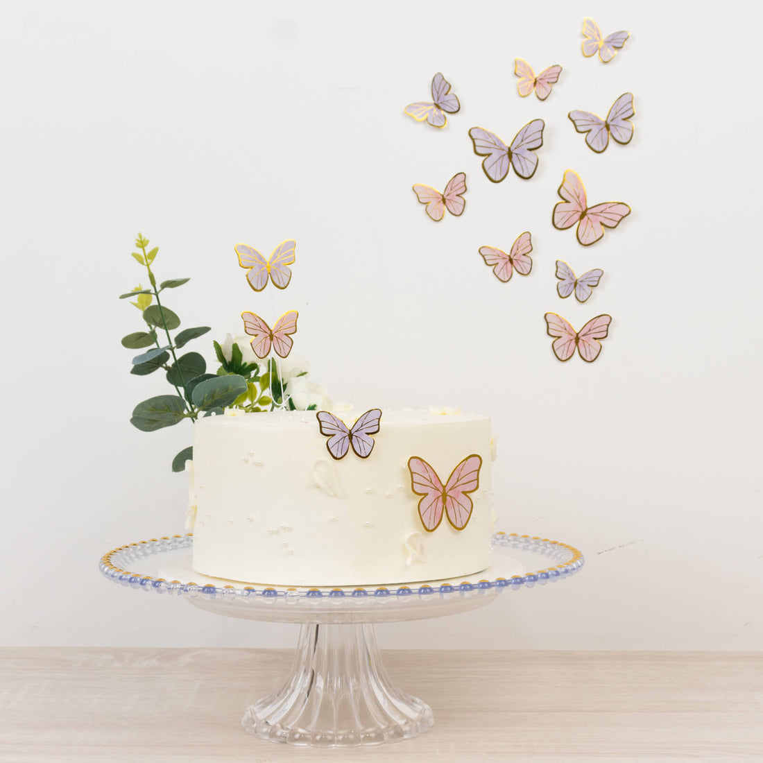 Butterfly-decorated cake on a glass stand with floral accents.