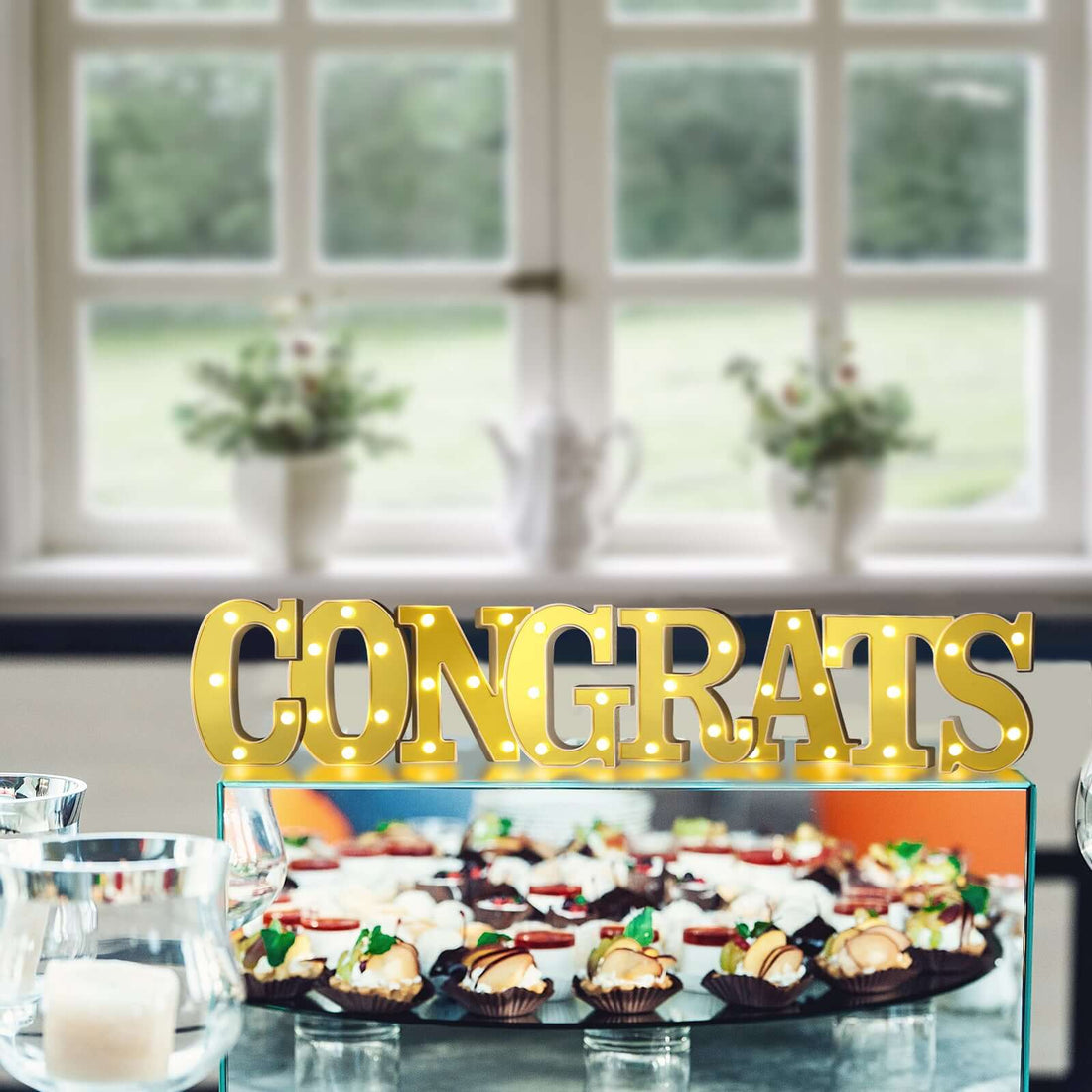 "Gold 'Congrats' sign with desserts at a festive celebration."