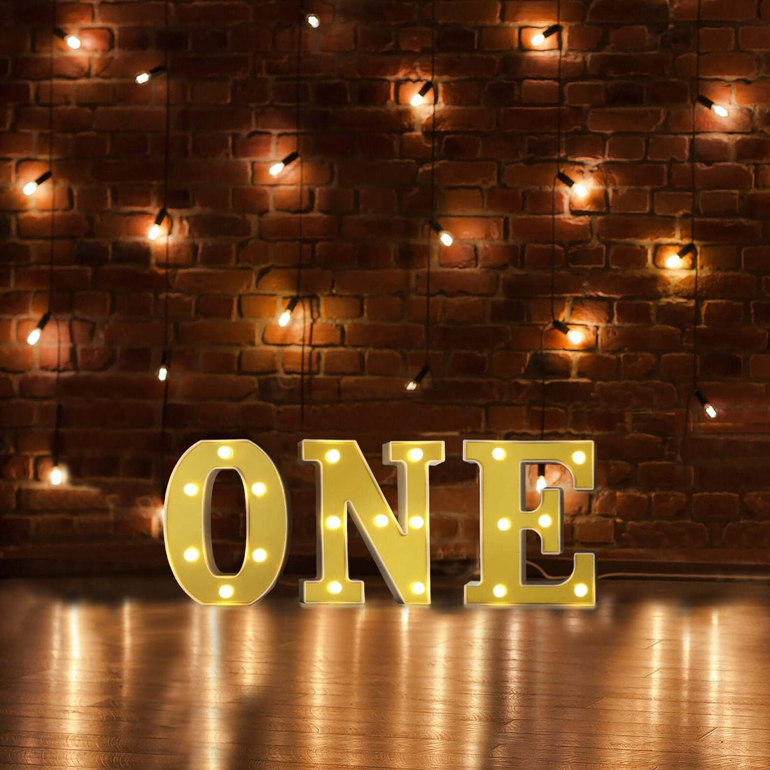 Illuminated marquee letters spelling "ONE" against a brick wall backdrop.