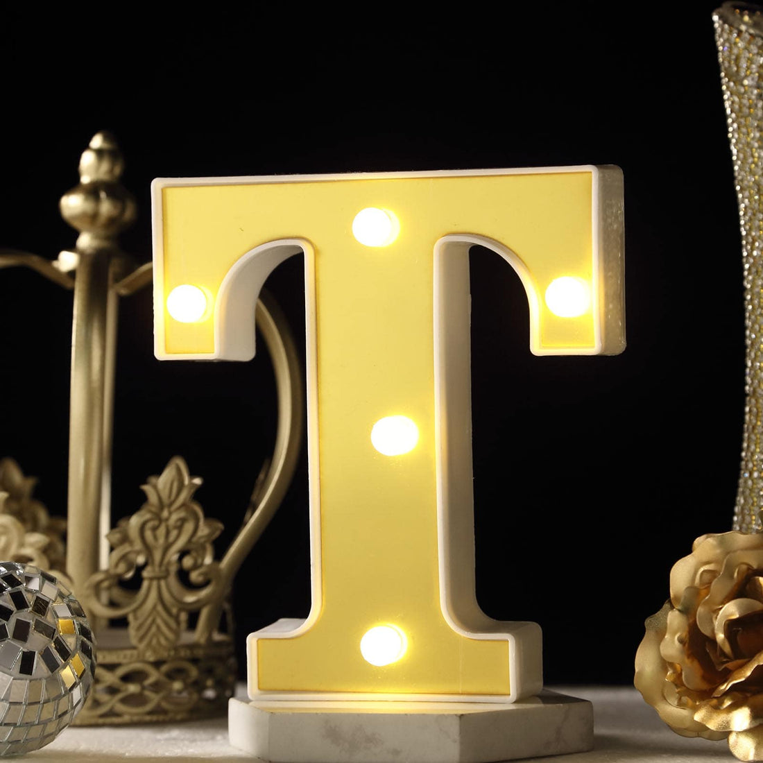Yellow marquee letter 'T' with lights on a decorative table setting.