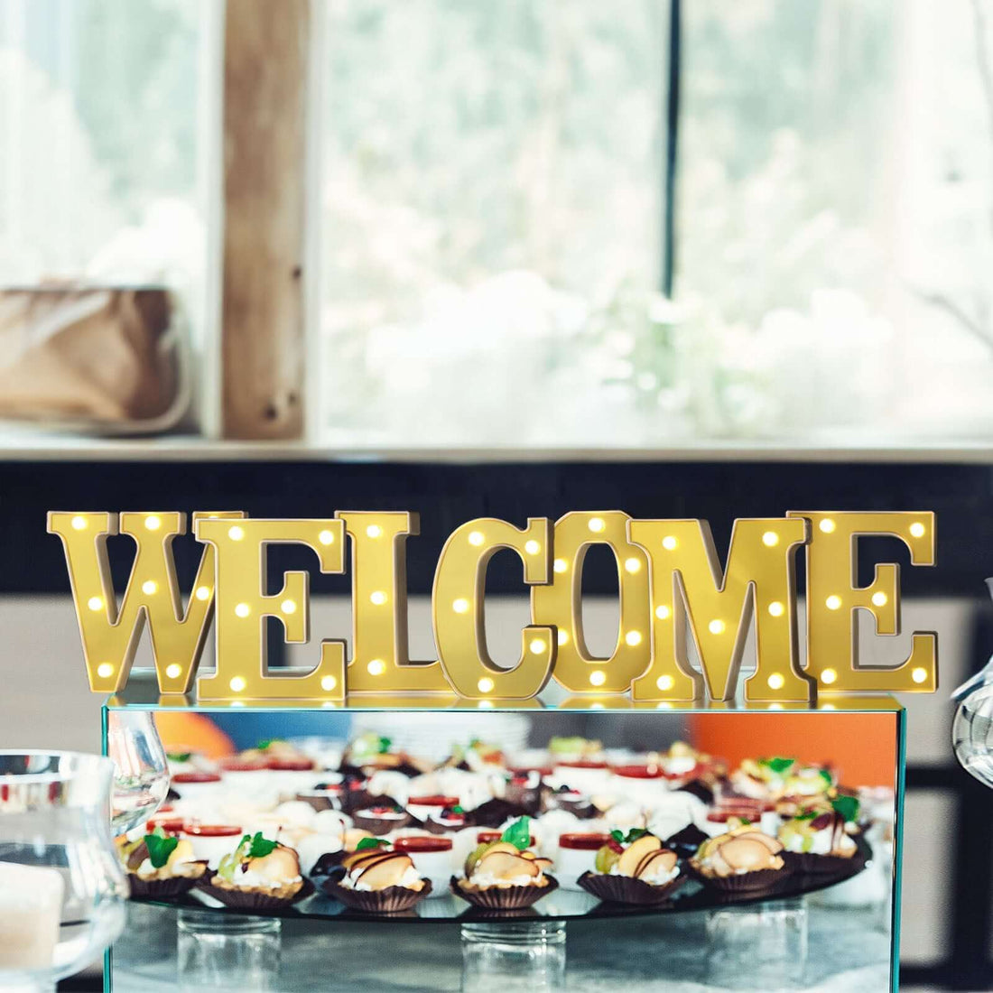 Welcome light-up sign with cupcakes in the background.