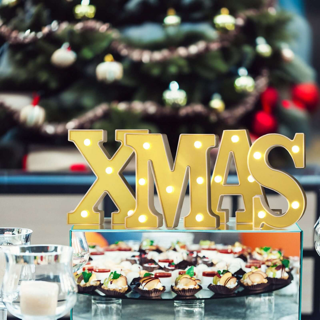 XMAS decorative sign with festive treats in the background.