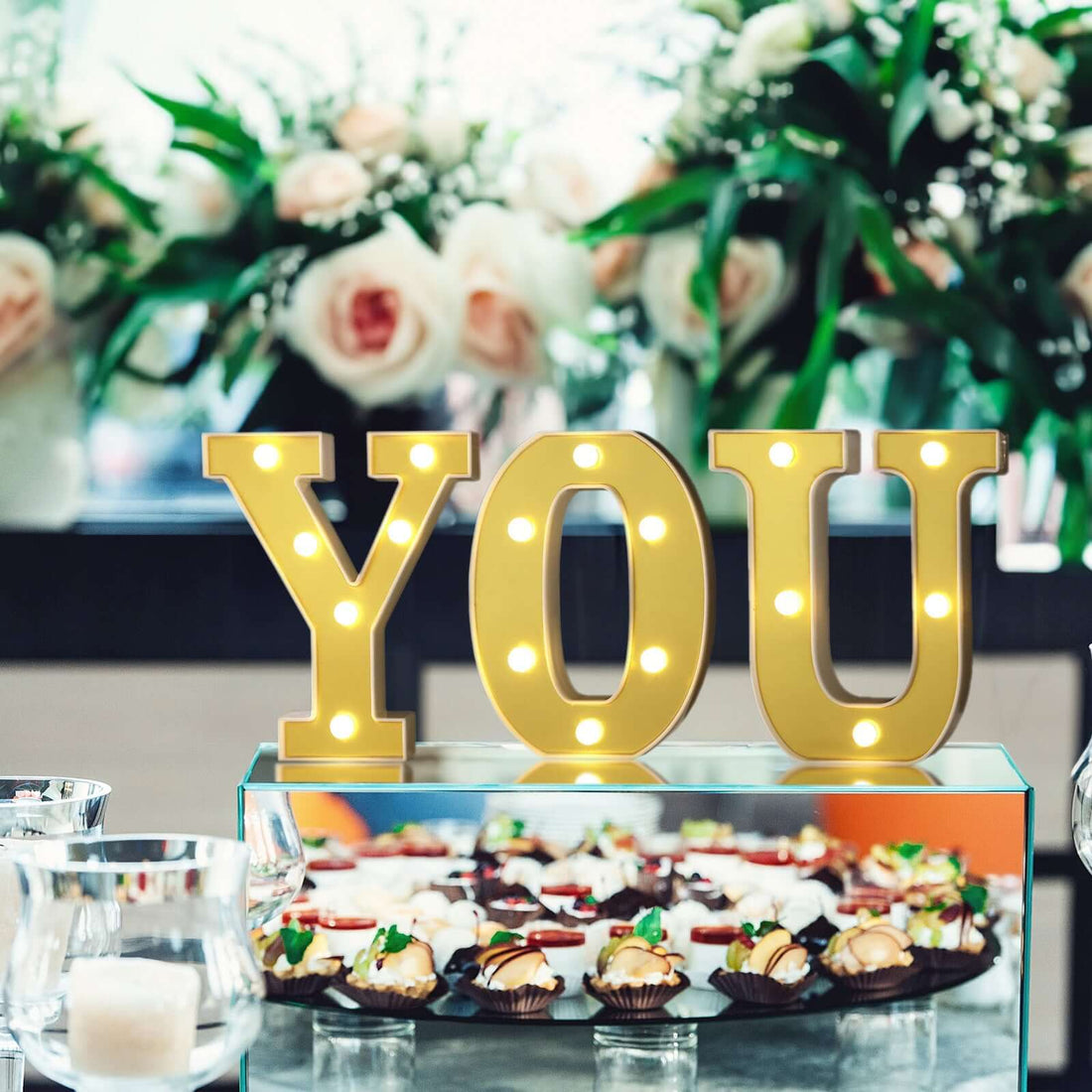 "Decorative 'YOU' sign with lights at a dessert display "