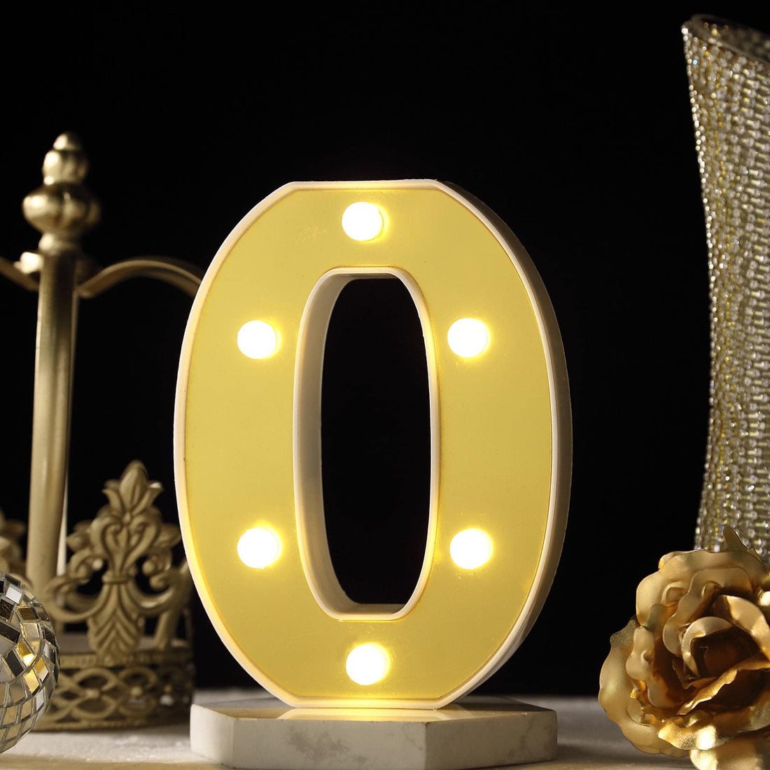 Illuminated marquee letter "O" with lights on a decorative table setting.