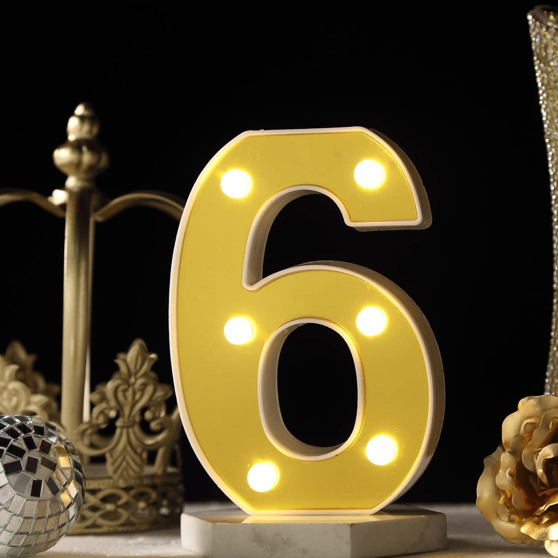 Illuminated yellow number 6 marquee light on a decorative table setting.
