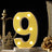 Illuminated number 9 decorative light with yellow bulbs on a marble base.