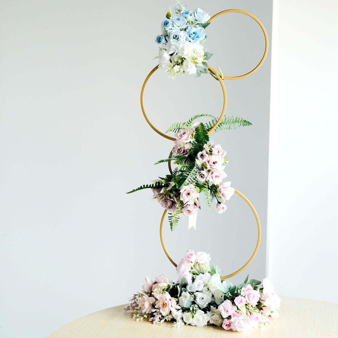 Floral display with gold rings and pastel roses on a table.