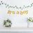 "It's a boy" banner with greenery and floral arrangement in a decor setting.