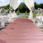 Wedding ceremony aisle runner in blush pink, lined with floral decorations and chairs.