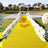 Elegant outdoor wedding setup with a yellow aisle and white floral arrangements.