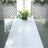 Floral arrangement on a glossy white table with decorative screens in the background.