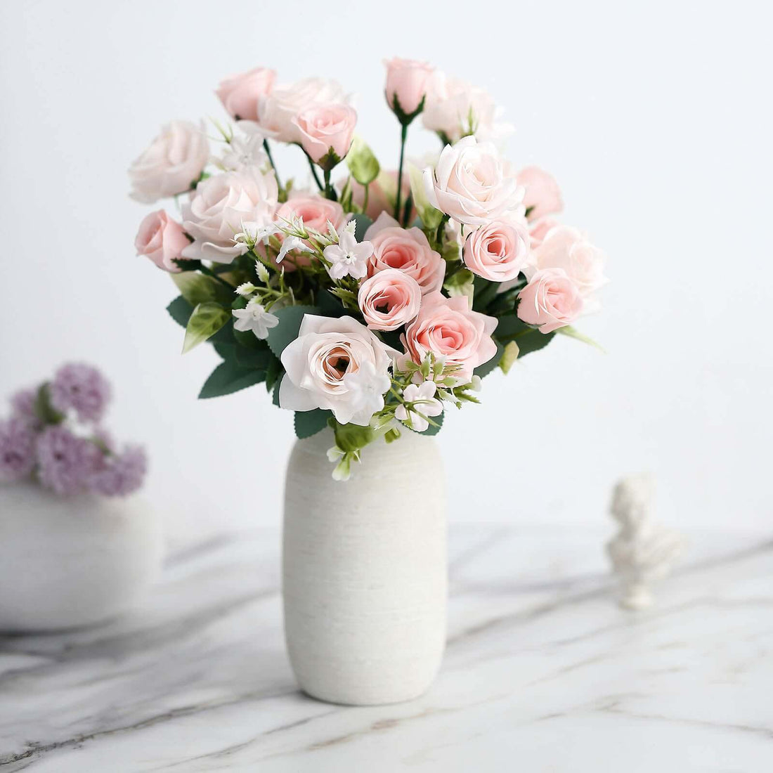 Pink rose bouquet in a white vase on a marble surface.