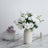 White rose bouquet in a minimalist vase on a marble surface.