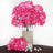 Pink artificial flowers in a glass vase with burlap and pearls.