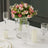 Elegant floral centerpiece with pink roses in a glass vase on a dining table.
