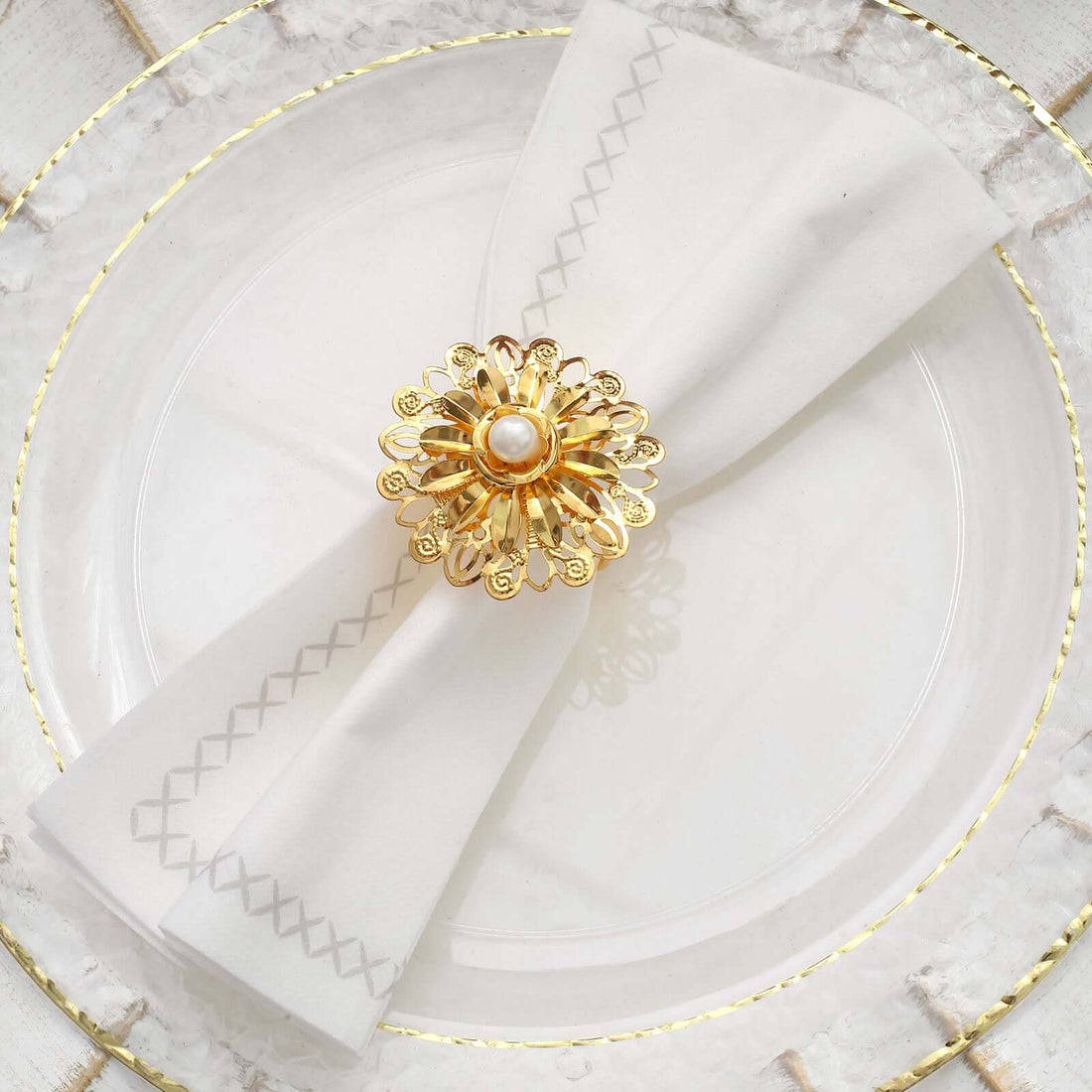 Elegant gold napkin ring with pearl on white napkin, styled on a decorative plate.