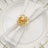 Elegant gold napkin ring with pearl on white napkin, styled on a decorative plate.