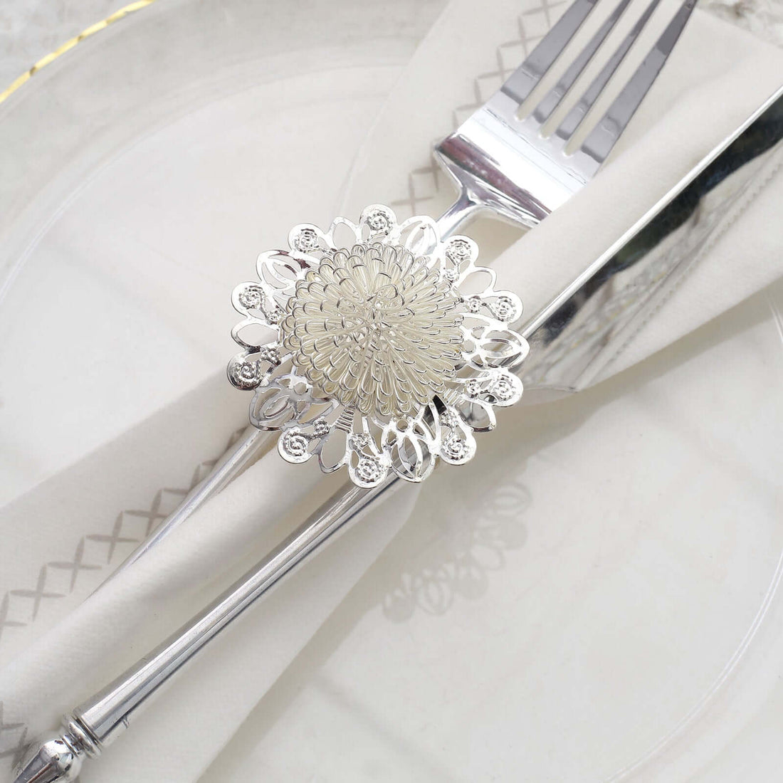 Silver decorative napkin holder with fork and knife on a plate.