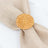 Rattan napkin ring holder on a beige cloth backdrop.