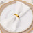 White napkin neatly folded with a gold napkin ring on an elegant plate.
