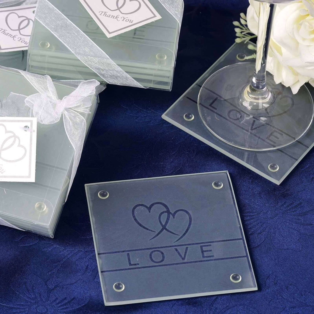 Engraved glass coasters with "LOVE" design for wedding favors.