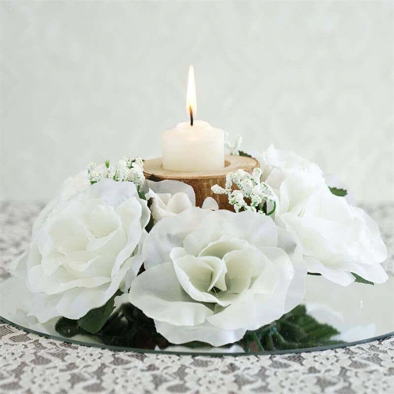 White floral centerpiece with a candle on a mirrored base.