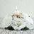 White floral centerpiece with a candle on a mirrored base.