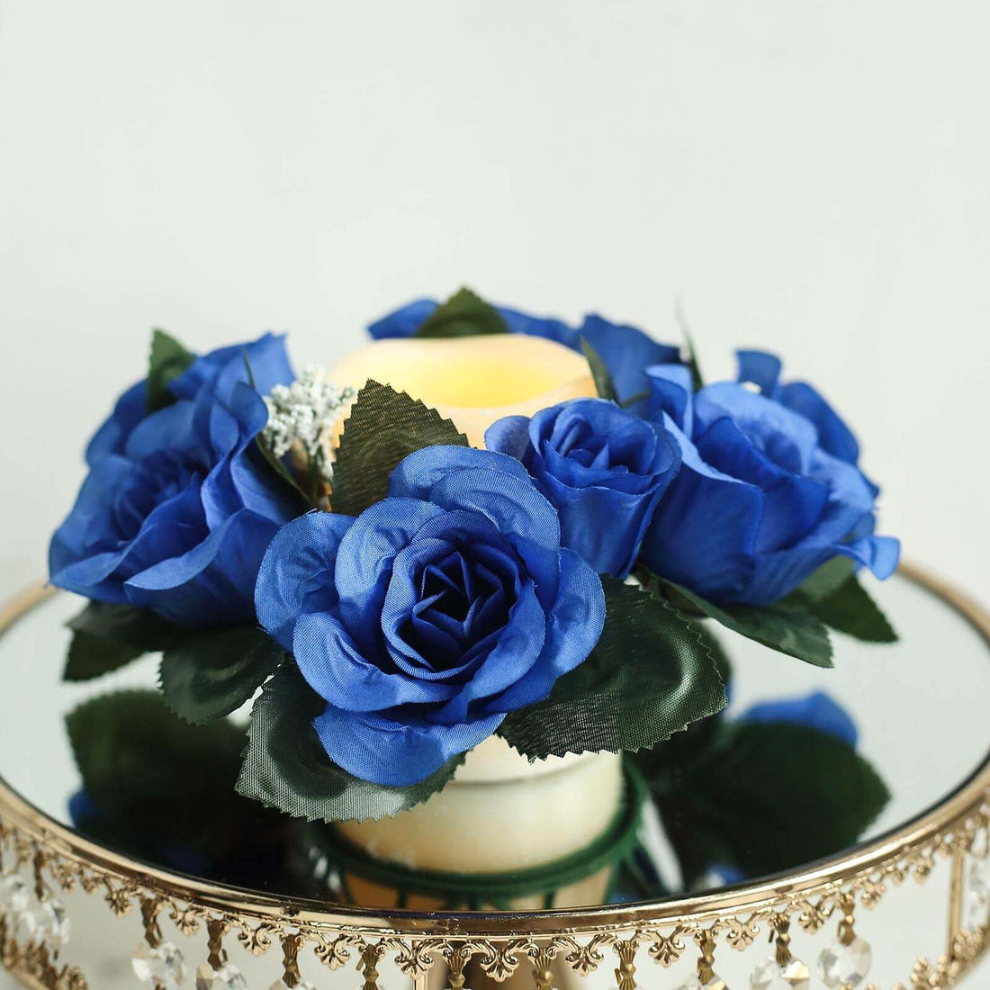 Blue rose bouquet with green leaves and a candle centerpiece.