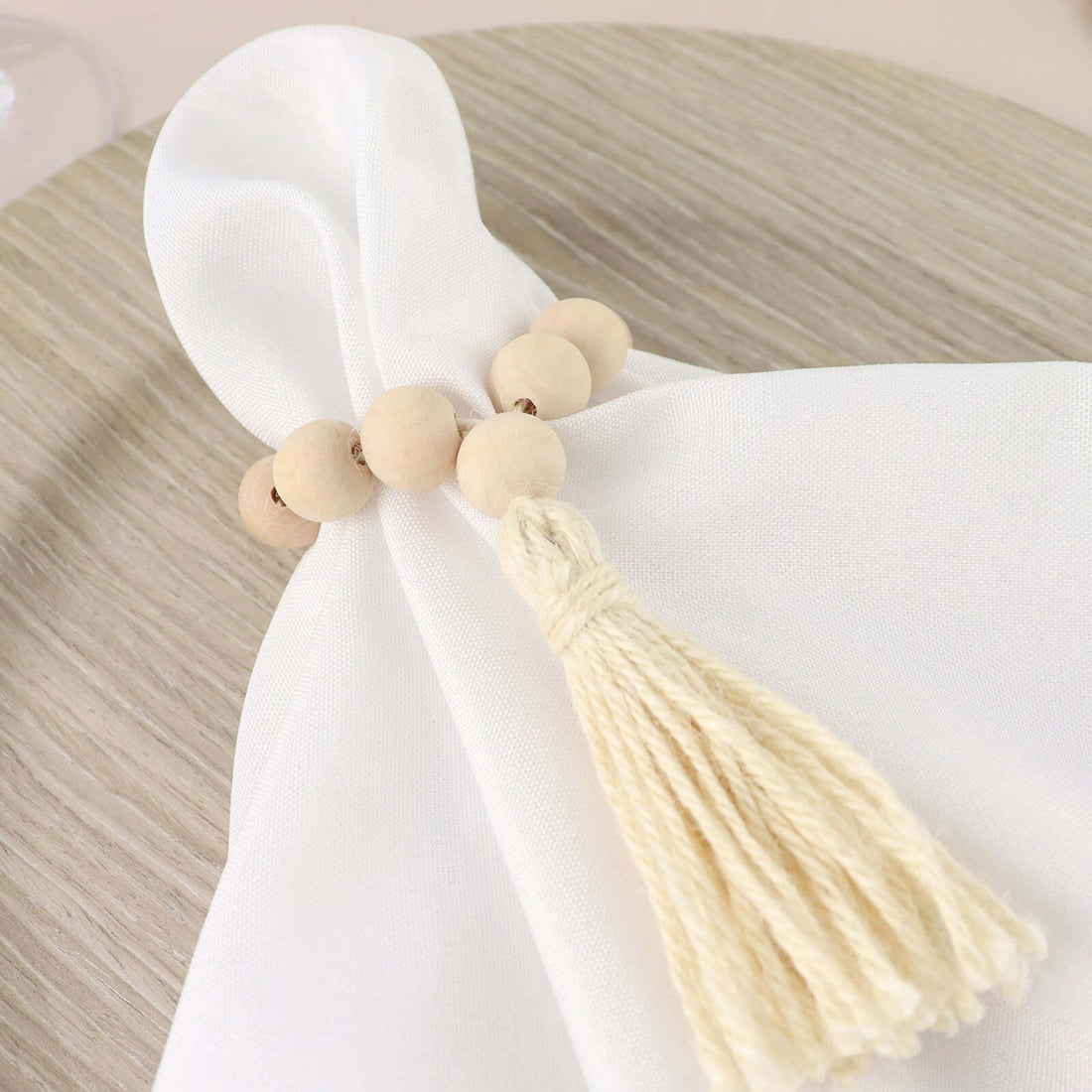 Beaded napkin ring with tassel on a white napkin.
