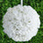 White floral ball decoration hanging against a green backdrop.