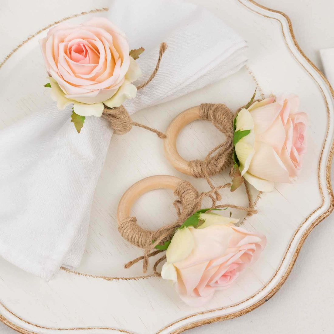 Rose-themed napkin rings and holder on a decorative plate.