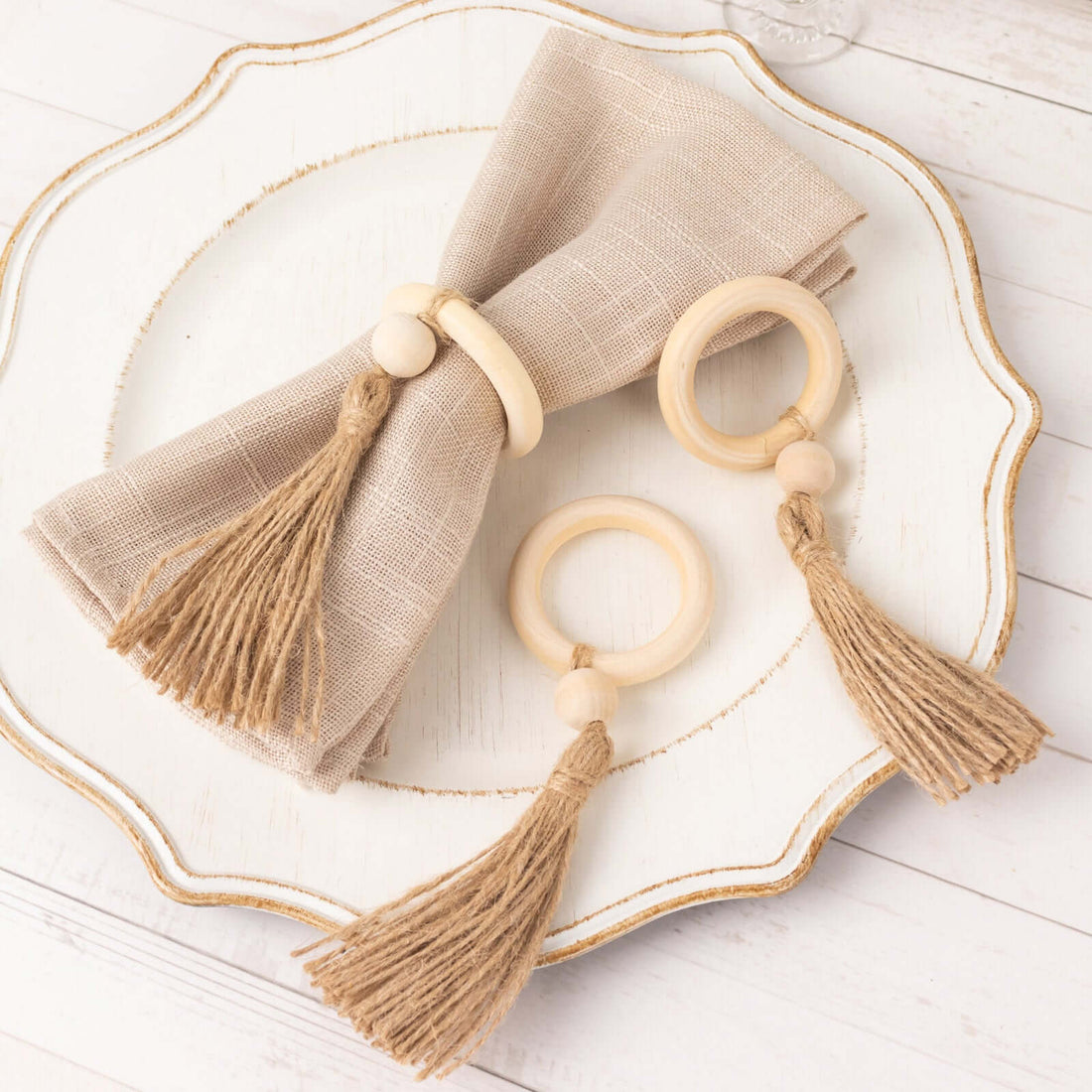 Natural wood napkin rings with tassels on a decorative plate.