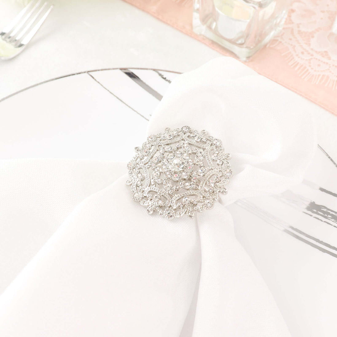 Elegant silver napkin holder with intricate design on a white napkin.