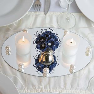 Elegant centerpiece with candles and floral arrangement on a mirrored tray.