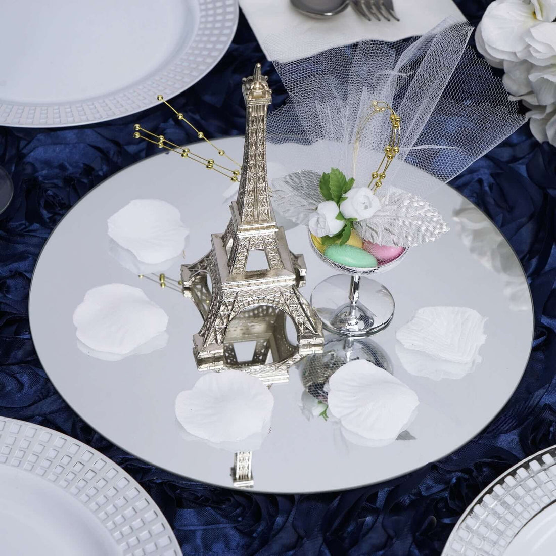 Eiffel Tower centerpiece on a reflective table setting with rose petals.