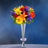 Colorful flower bouquet in a clear vase against a blue background.