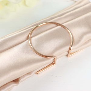 Rose gold napkin ring on satin fabric.