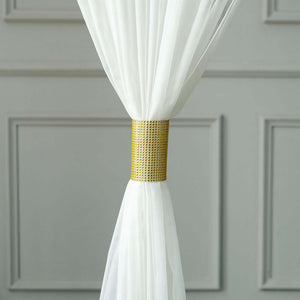 White sheer curtain tied with a gold decorative strap.