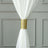 White sheer curtain tied with a gold decorative strap.