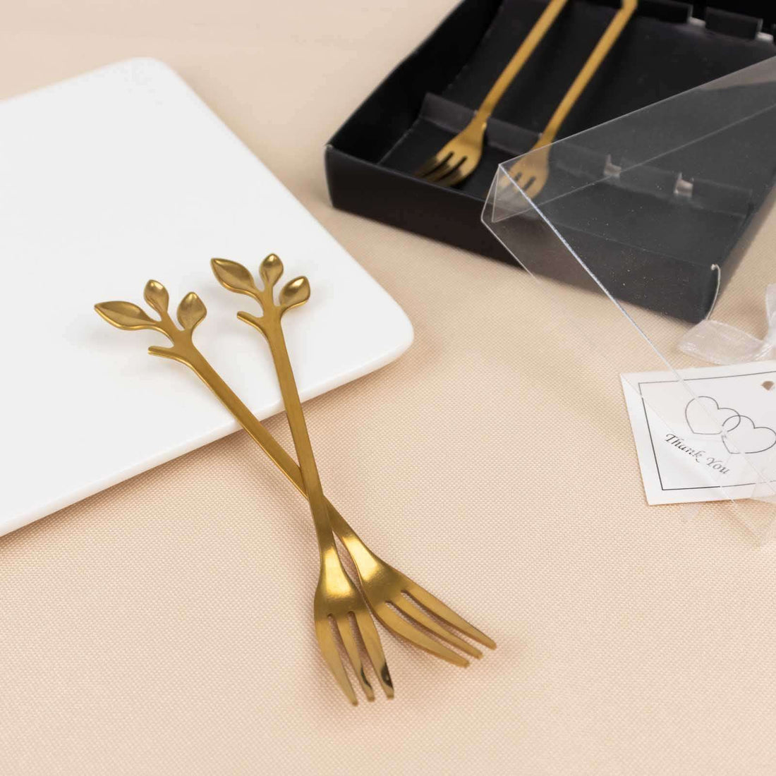 Gold leaf design appetizer forks on a soft background.