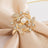 Gold floral napkin ring with pearl and rhinestones on satin fabric.