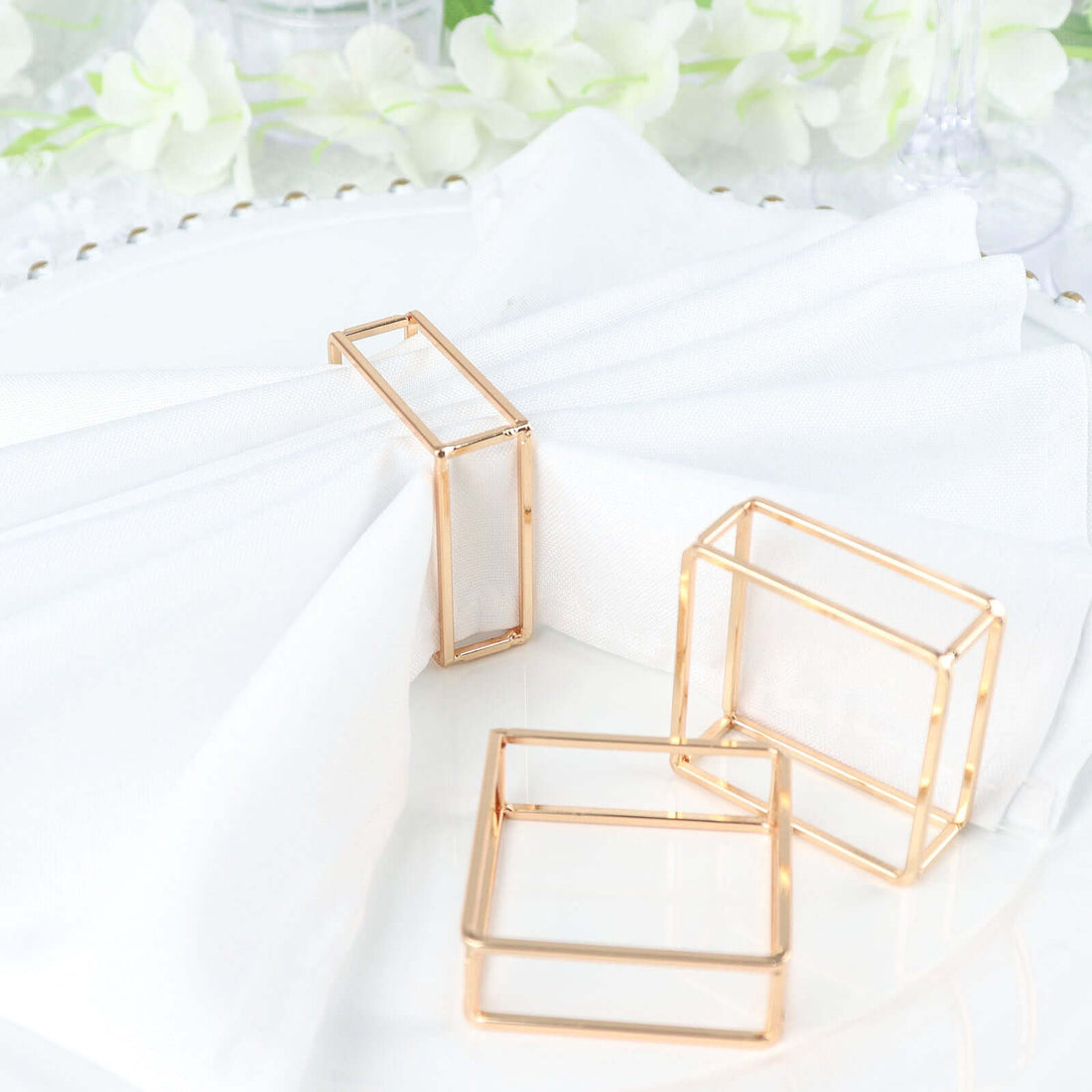 Gold geometric napkin rings on a white plate with napkins.