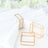 Gold geometric napkin rings on a white plate with napkins.
