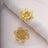 Gold floral napkin ring with intricate design and rhinestone accent.